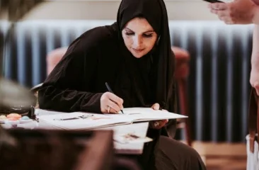 Writer Kamalia Talhaoui writing at a table.